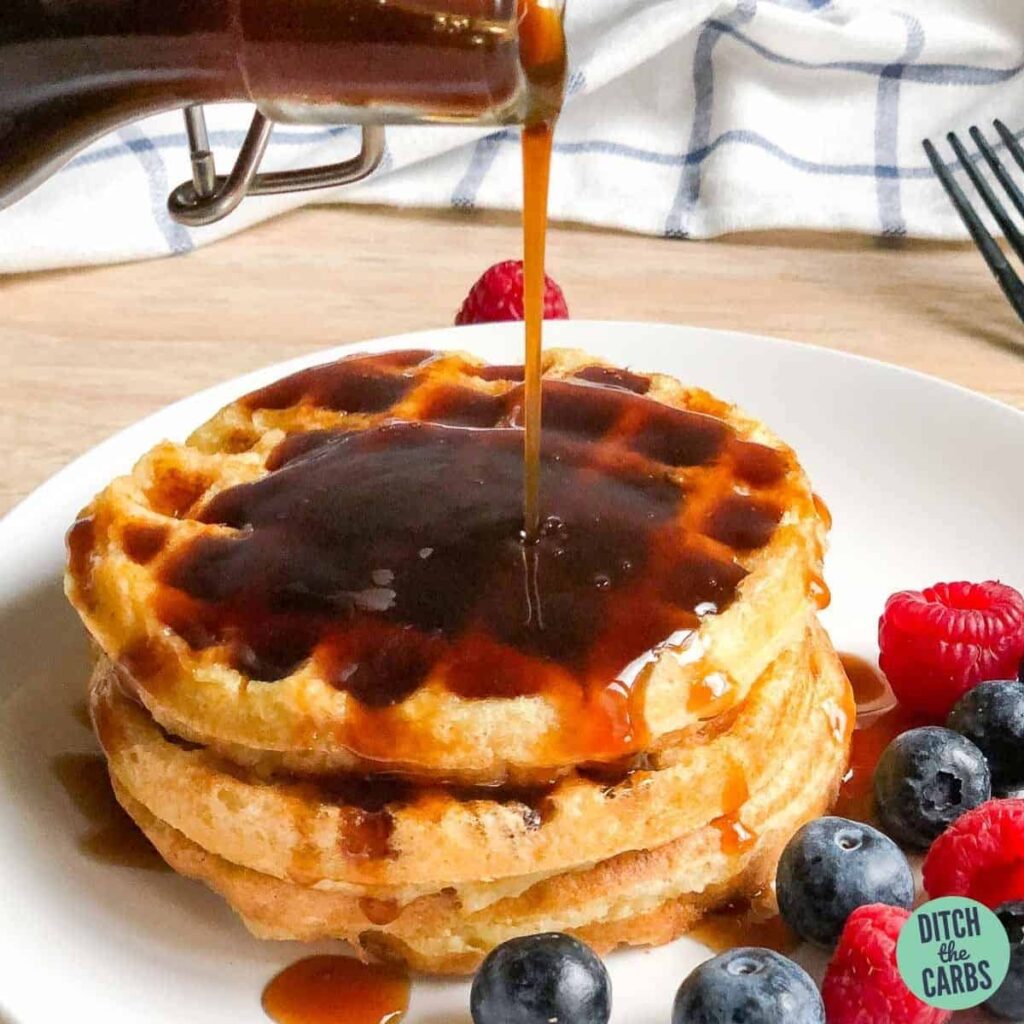 homemade sugar-free keto maple syrup being poured onto gluten-free waffles